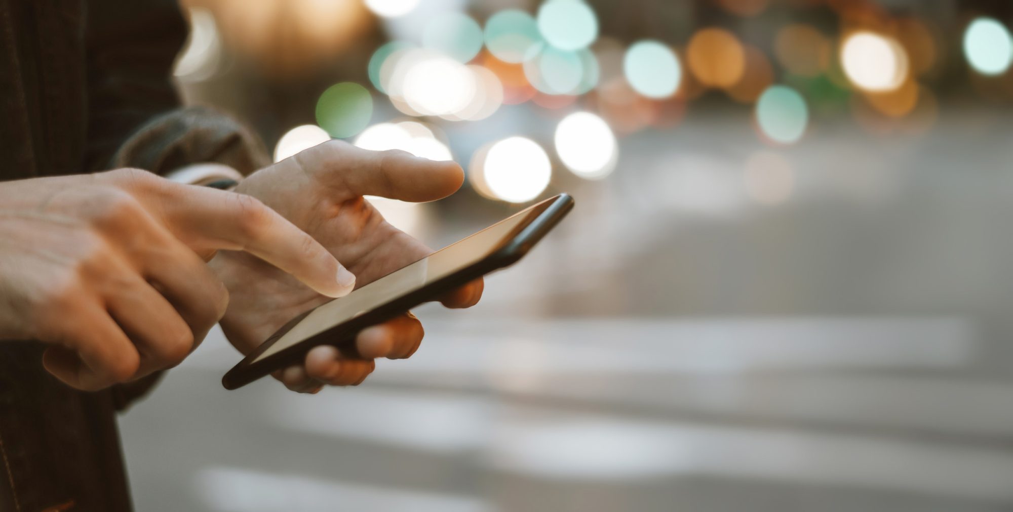 Close-up of male hands with smartphone outdoors. Close-up photo of male hands with smartphone outdoors, city street